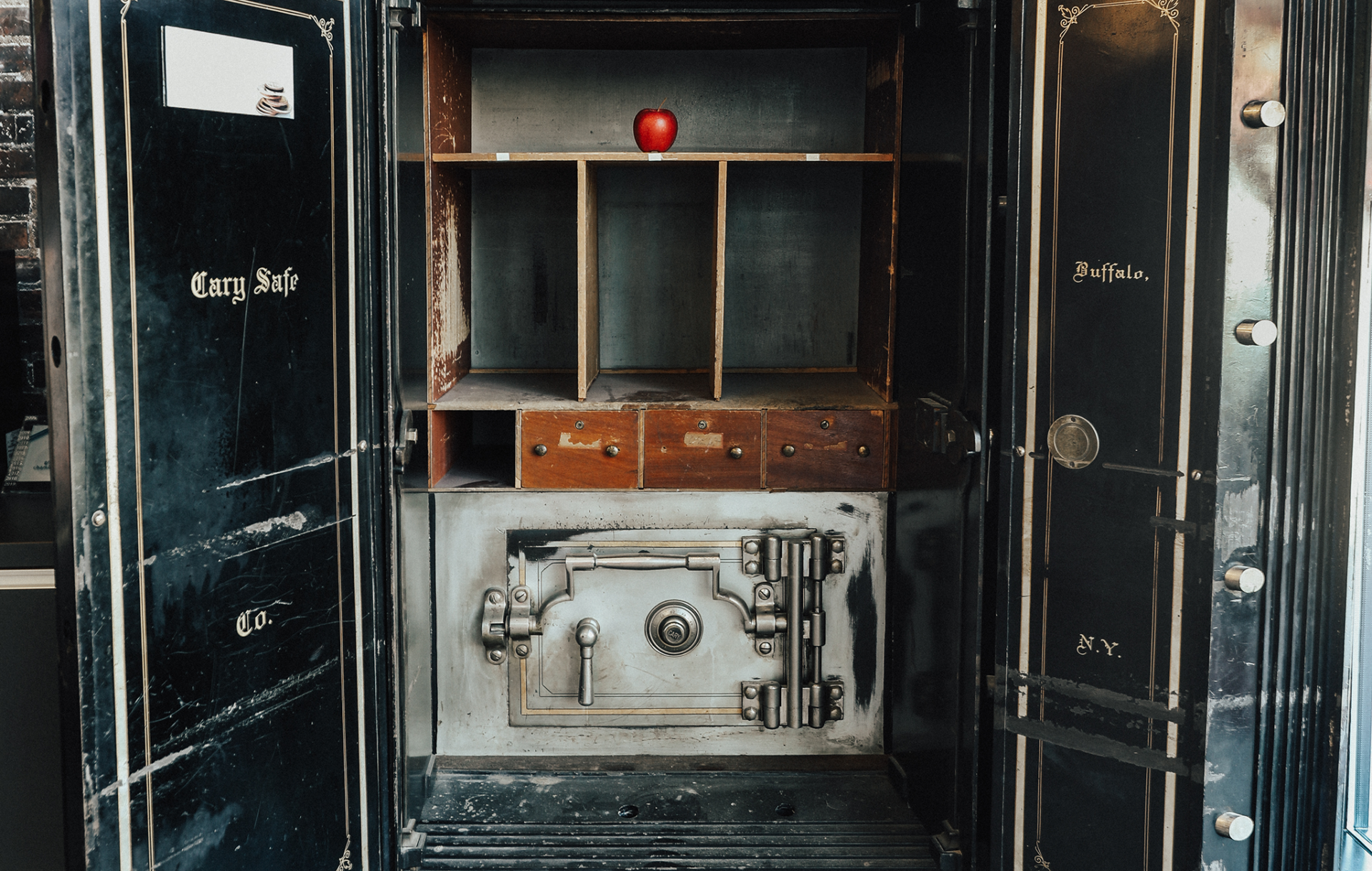 An apple sits on a shelf inside a vintage bank vault.