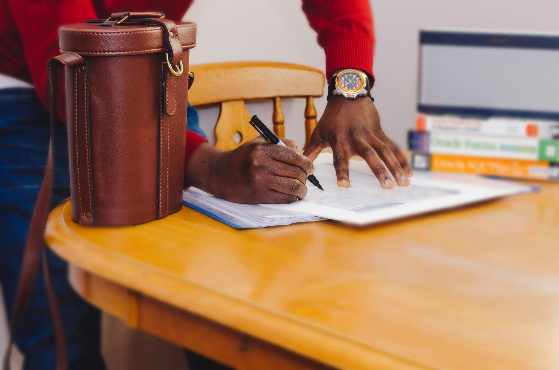 A man wearing a red sweater signs a contract.