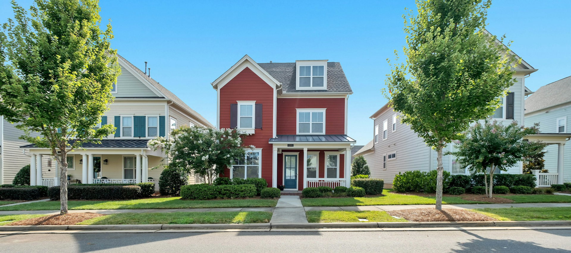 A red home flanked by two trees.